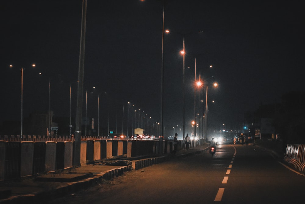 Uma rua escura à noite com luzes de rua