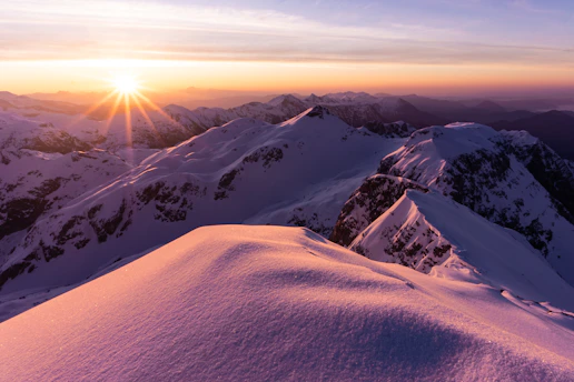 A breathtaking sunrise over the snowy peaks of Saint Moritz, with golden light reflecting on the icy lake.