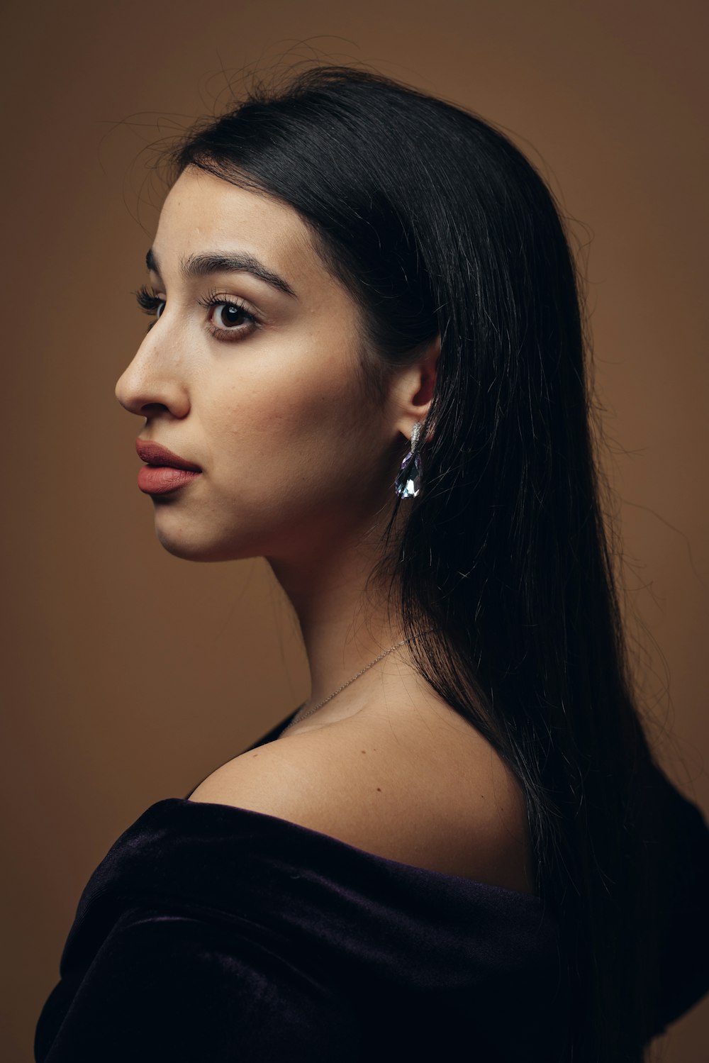 a woman with long black hair wearing earrings