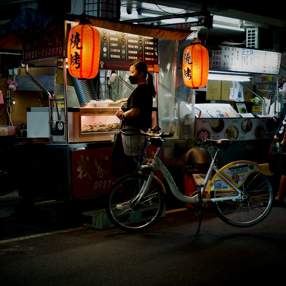 a man standing next to a bike in front of a food stand