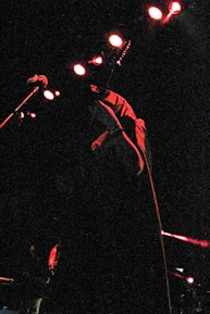 Close-up of a musician playing an electric guitar with spooky stage decorations in the background.