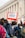 People are participating in a protest with a visible sign that reads 'CEASEFIRE NOW!' The crowd is dressed in casual clothing with backpacks visible, gathered in front of a classical-style building with columns.