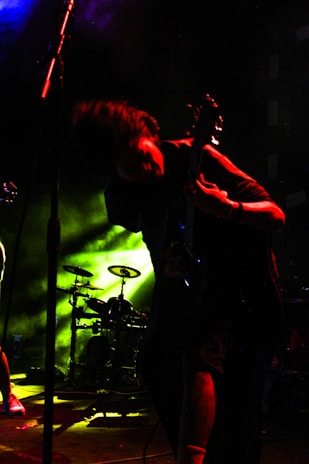 Energetic artist performing live with vibrant yellow stage lights and dark background