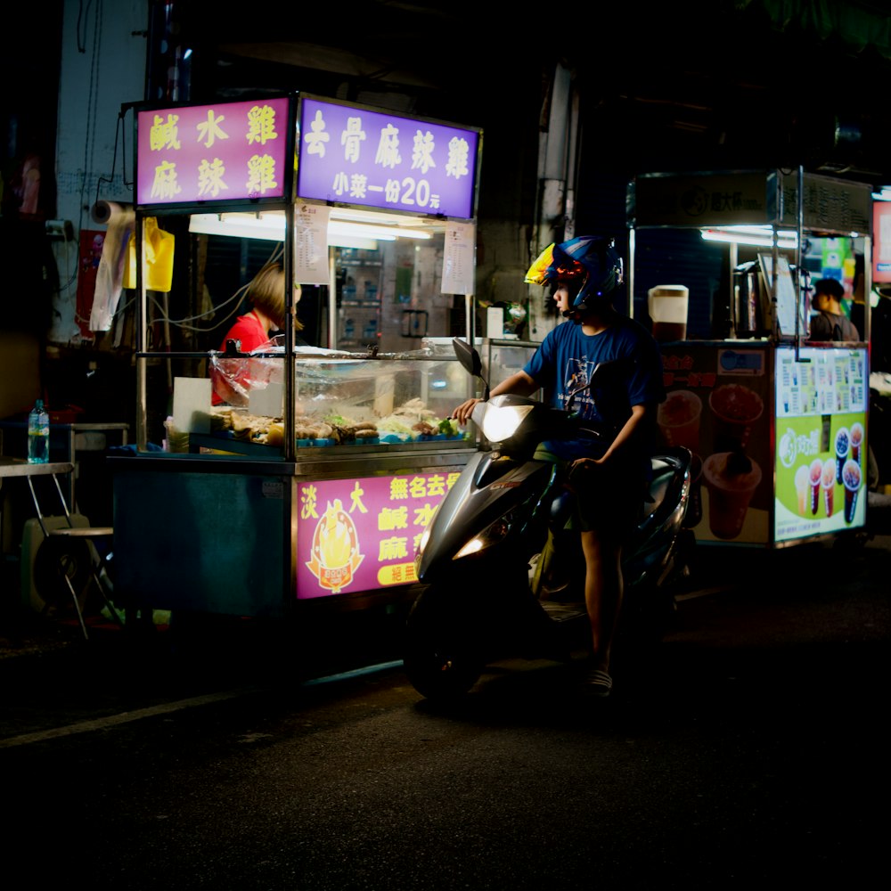 a man riding a motorcycle next to a food cart