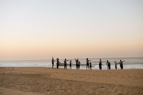 a group of people standing on top of a sandy beach
