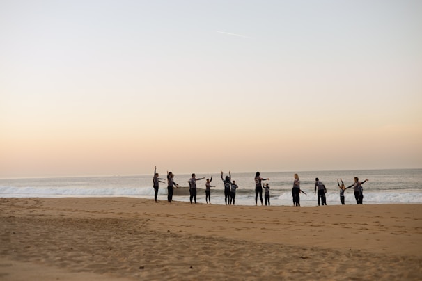 A group practicing synchronized breathwork on a quiet beach at sunrise, waves softly lapping nearby.