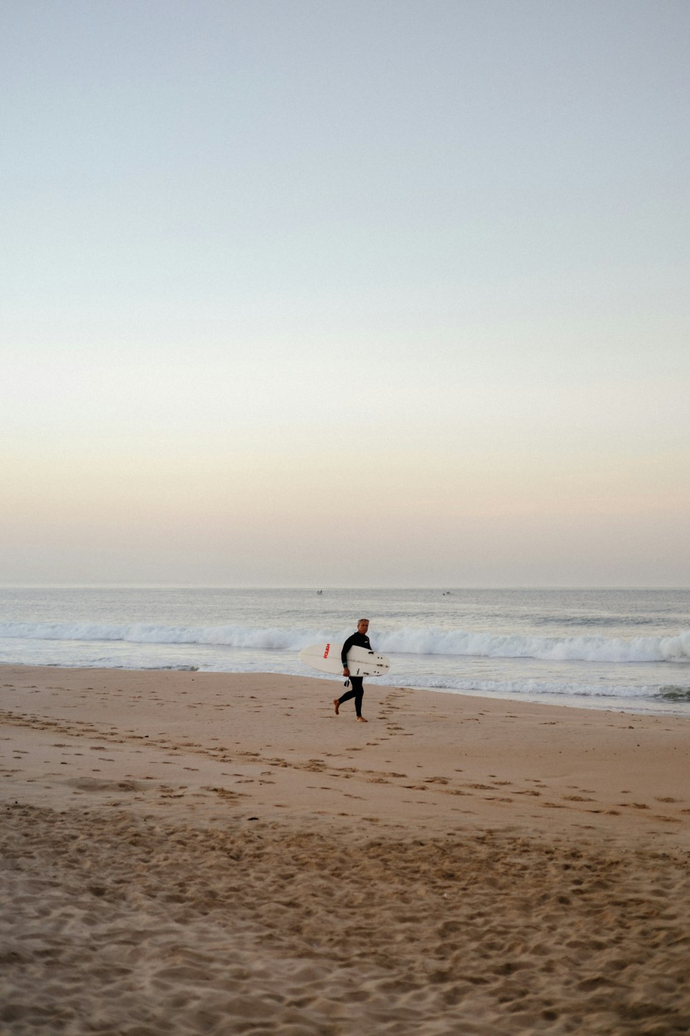 a person running on a beach with a surfboard