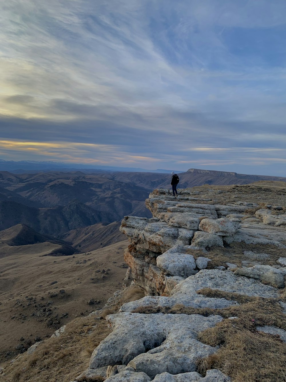 una persona de pie en la cima de un acantilado rocoso