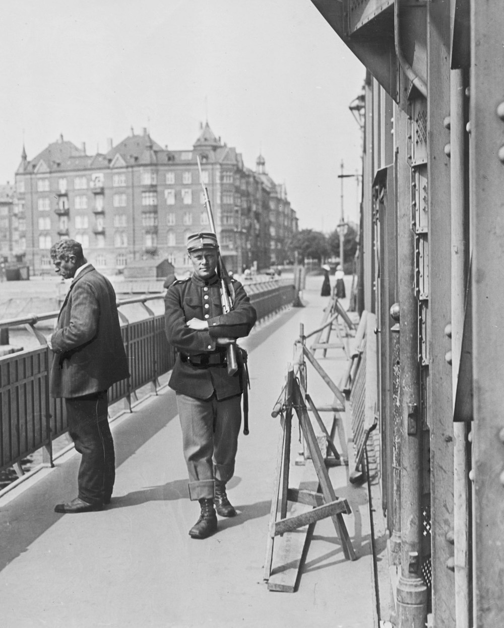 an old black and white photo of two men on a bridge