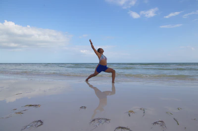 A person practicing yoga at sunrise on a quiet beach with gentle waves.