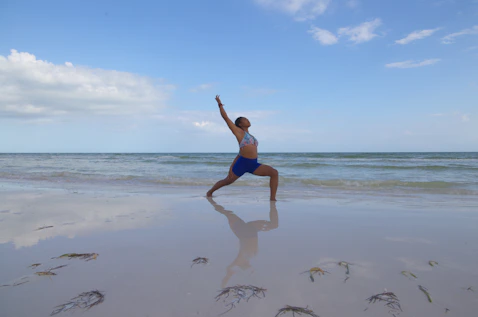 A person practicing yoga at sunrise on a quiet beach with gentle waves.