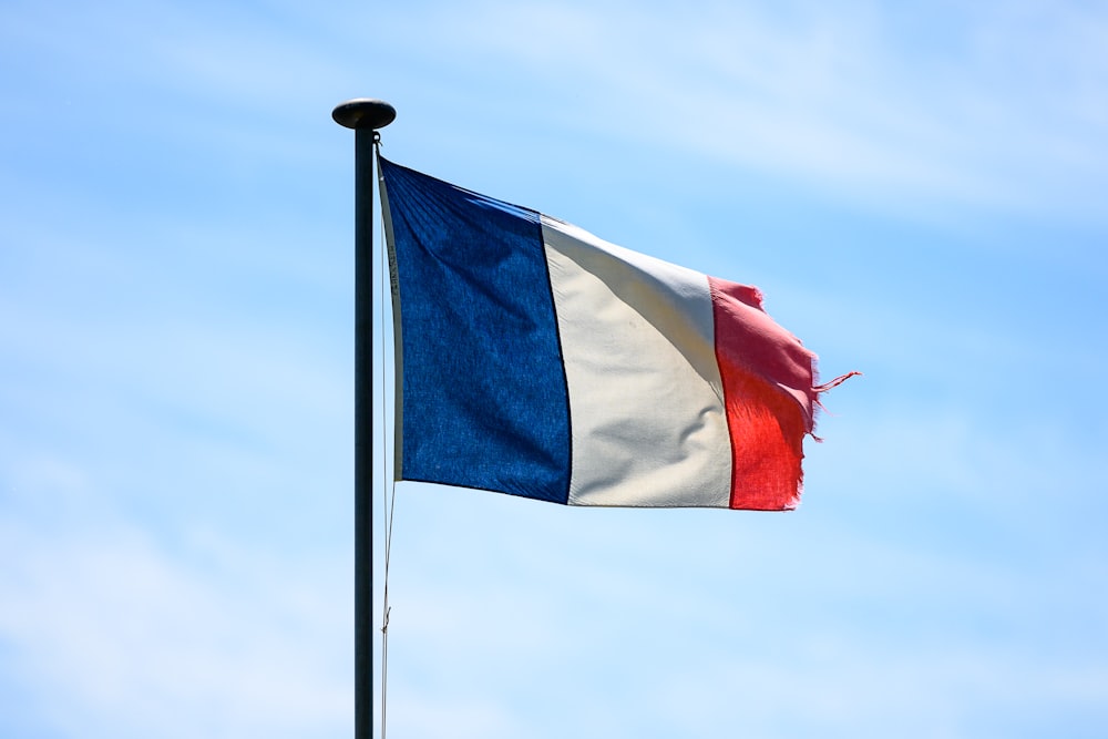 a flag flying in the wind with a blue sky in the background