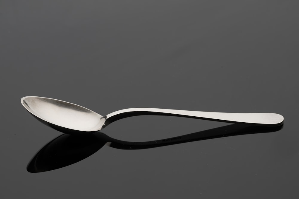 a spoon with a curved handle on a black surface