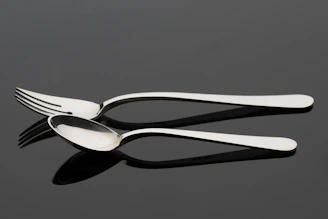 Shiny stainless steel cutlery and serving utensils displayed on a linen cloth.