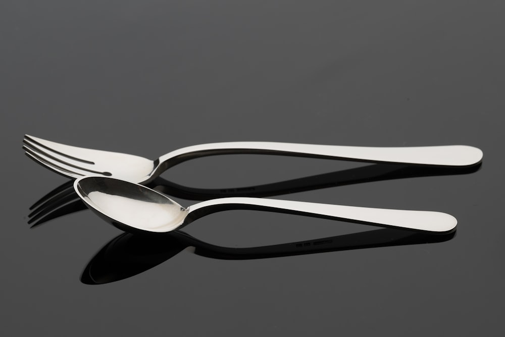 two forks and a spoon on a black surface