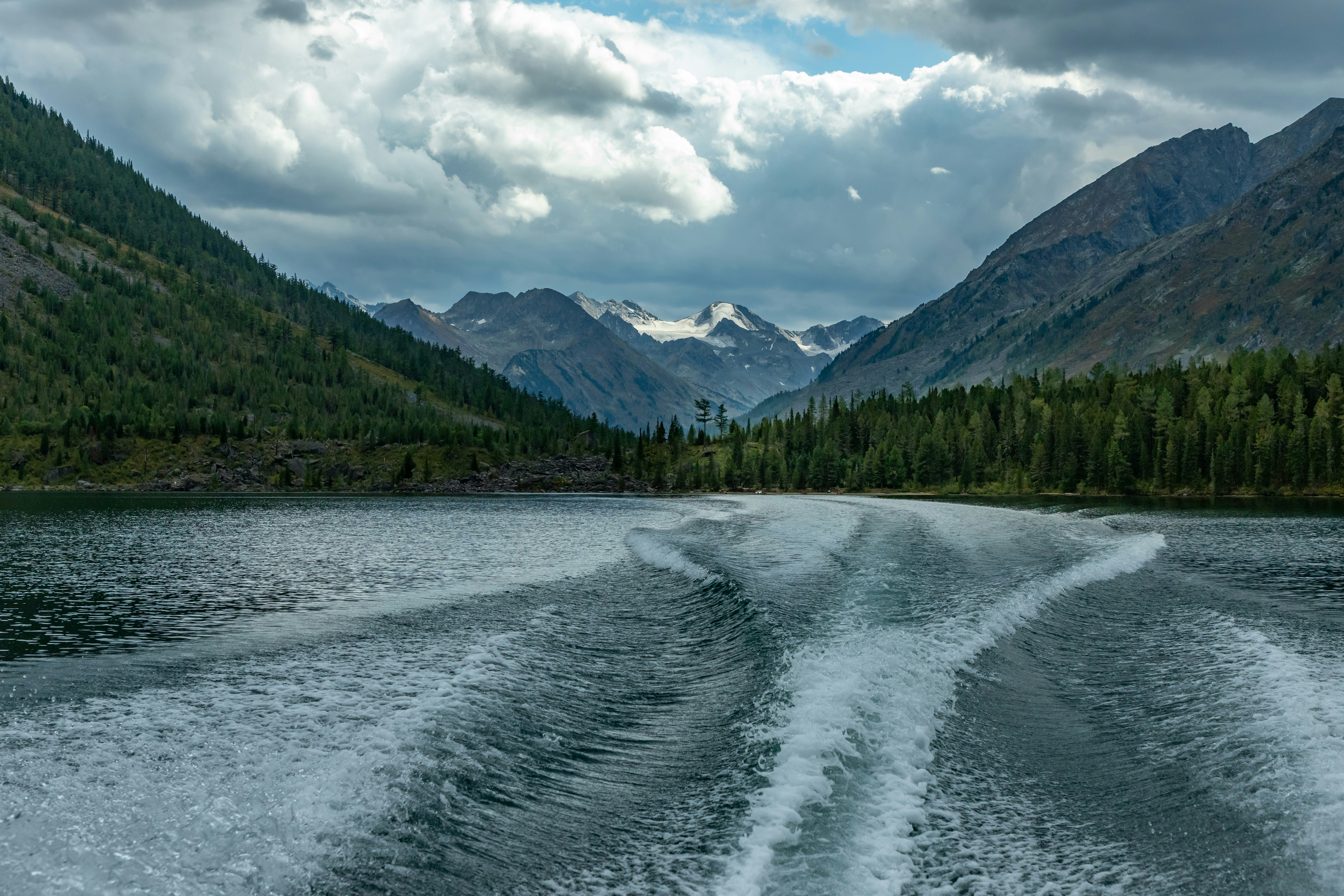 the wake of a boat on a lake with mountains in the background