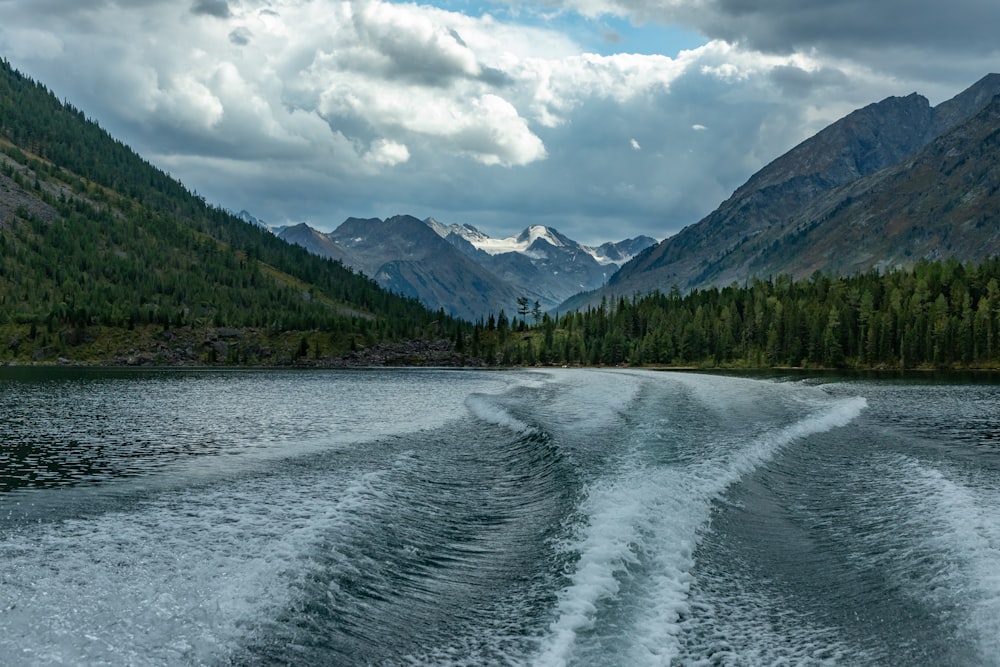 the wake of a boat on a lake with mountains in the background