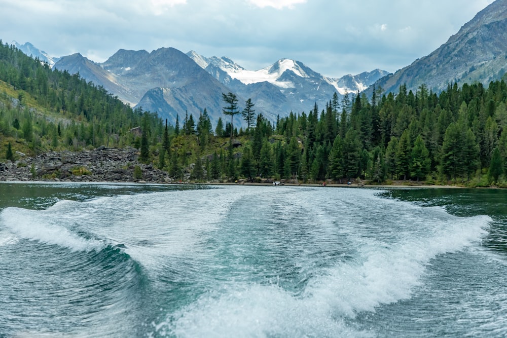 the wake of a boat in the water with mountains in the background