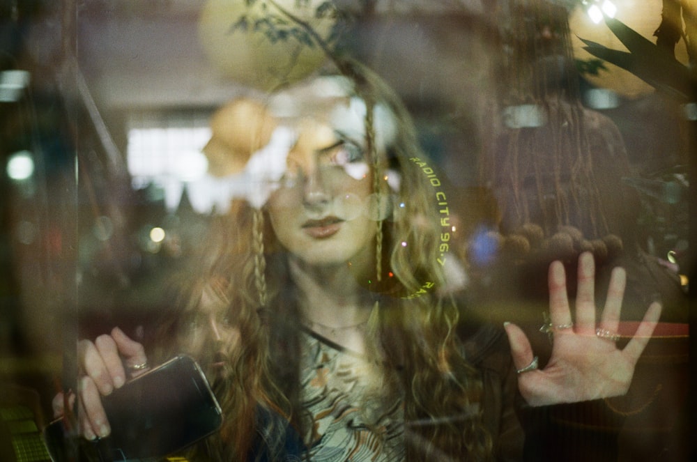a woman standing behind a glass window with her hands in the air