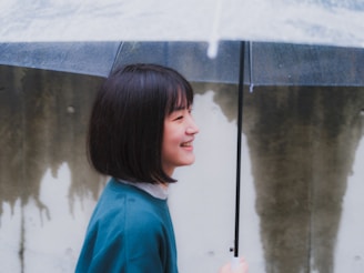 a young girl holding an umbrella in the rain