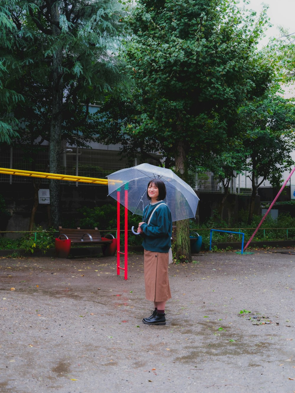 una mujer sosteniendo un paraguas transparente en un parque