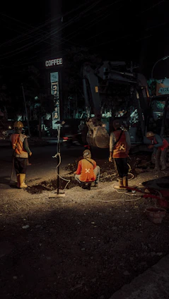 A close-up shot of workers carefully laying underground cables at a construction site during golden hour.
