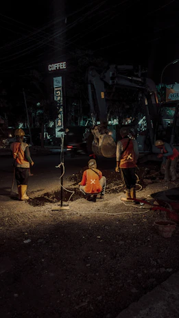 A modern infrastructure project site with workers inspecting a city road under construction.