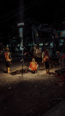 Construction workers laying cables along a busy urban road as part of a street lighting project.
