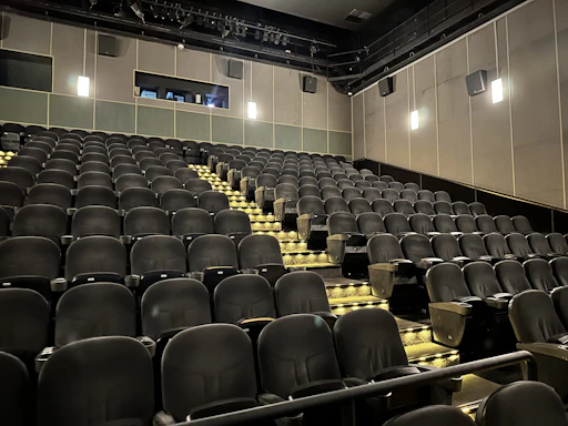 A cozy, minimalist theatre lobby with warm lighting and a simple contact desk.