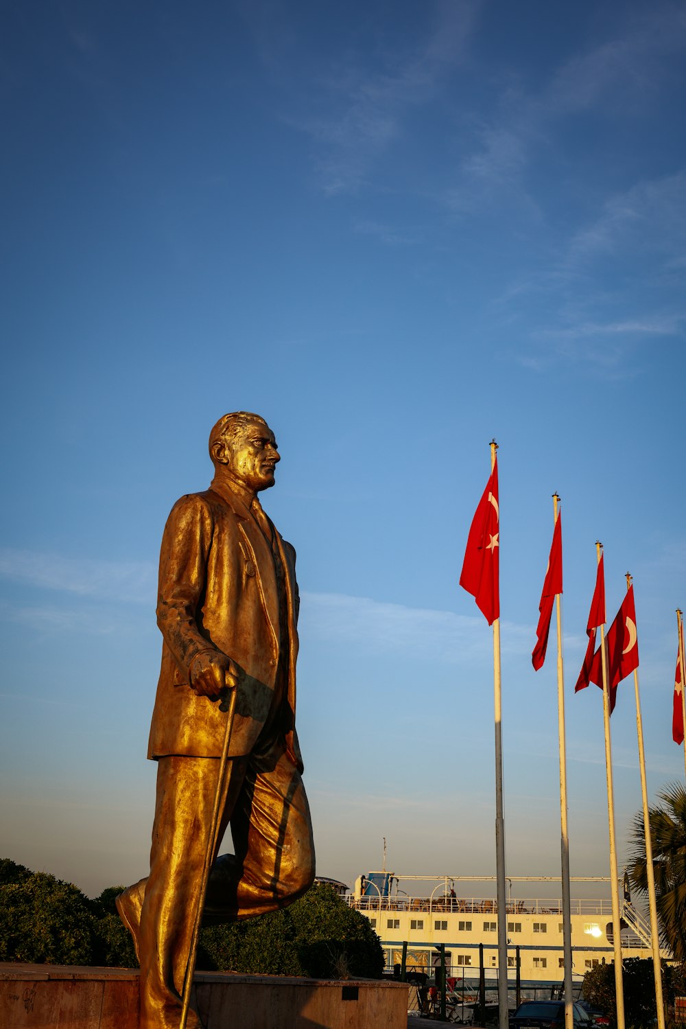 a statue of a man holding a cane in front of flags
