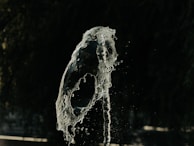 Playful splash of cloudy bongwater frozen mid-air over a wooden floor.