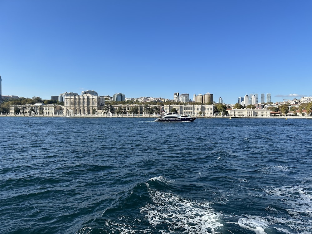 a boat traveling on the water in front of a city