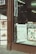 A storefront displays framed artwork and posters, including a prominent New Yorker cover and botanical illustrations of strawberries. The window is framed by a dark brown wood facade, and the interior is softly lit with fluorescent lights.