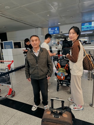 A friendly service agent helping a traveler with documents at a busy Cambodian airport.