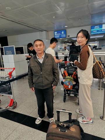 Smiling travelers receiving help with their luggage at the airport counter.