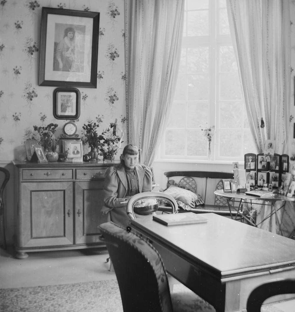 a black and white photo of a woman sitting at a table