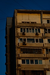 Apartment building exterior with maintenance worker checking electrical systems.