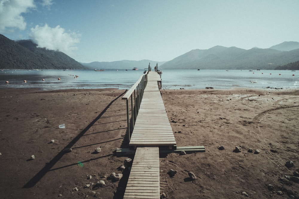 a long wooden dock sitting on top of a sandy beach