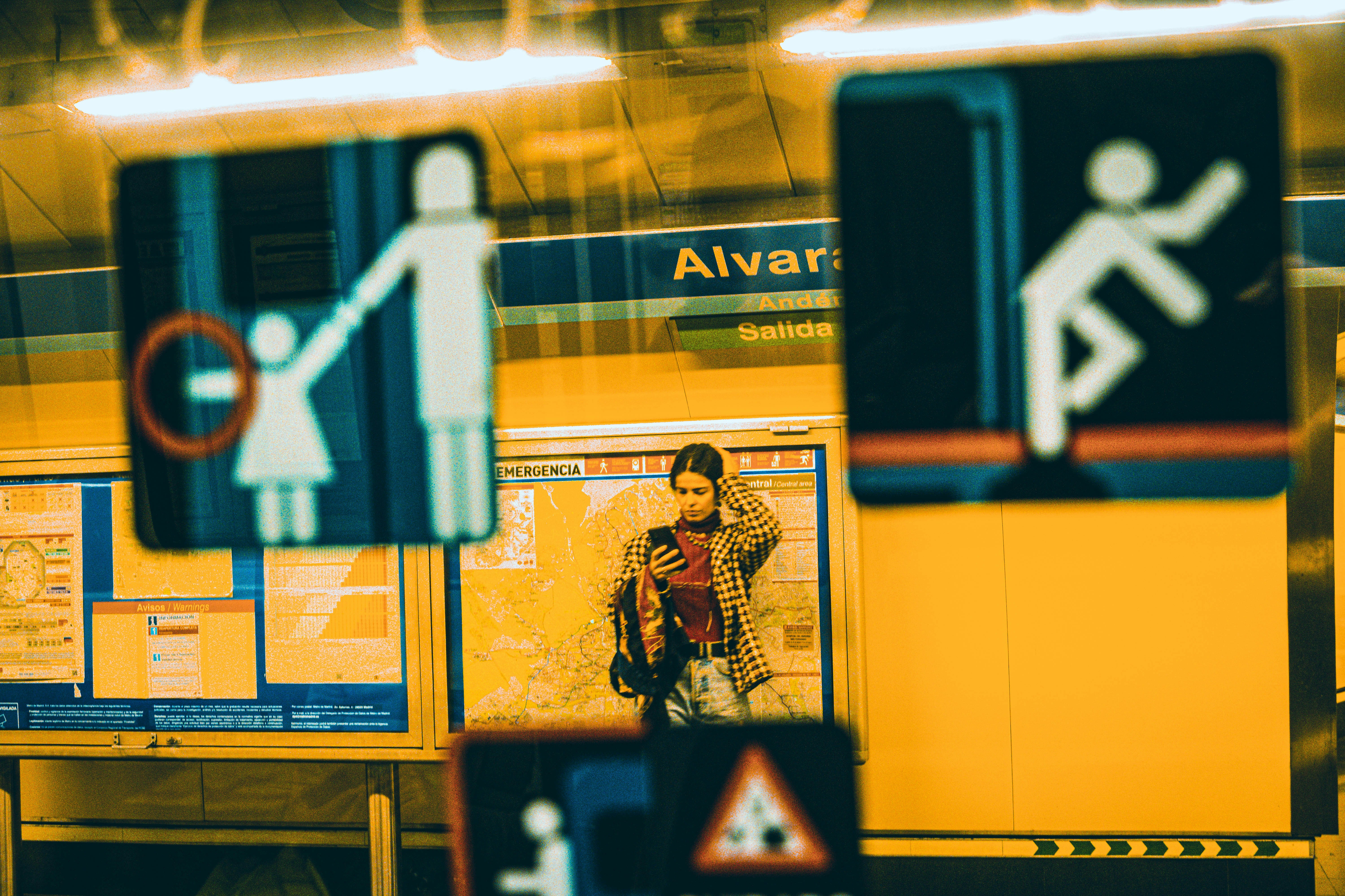 a woman standing in a train station next to a sign