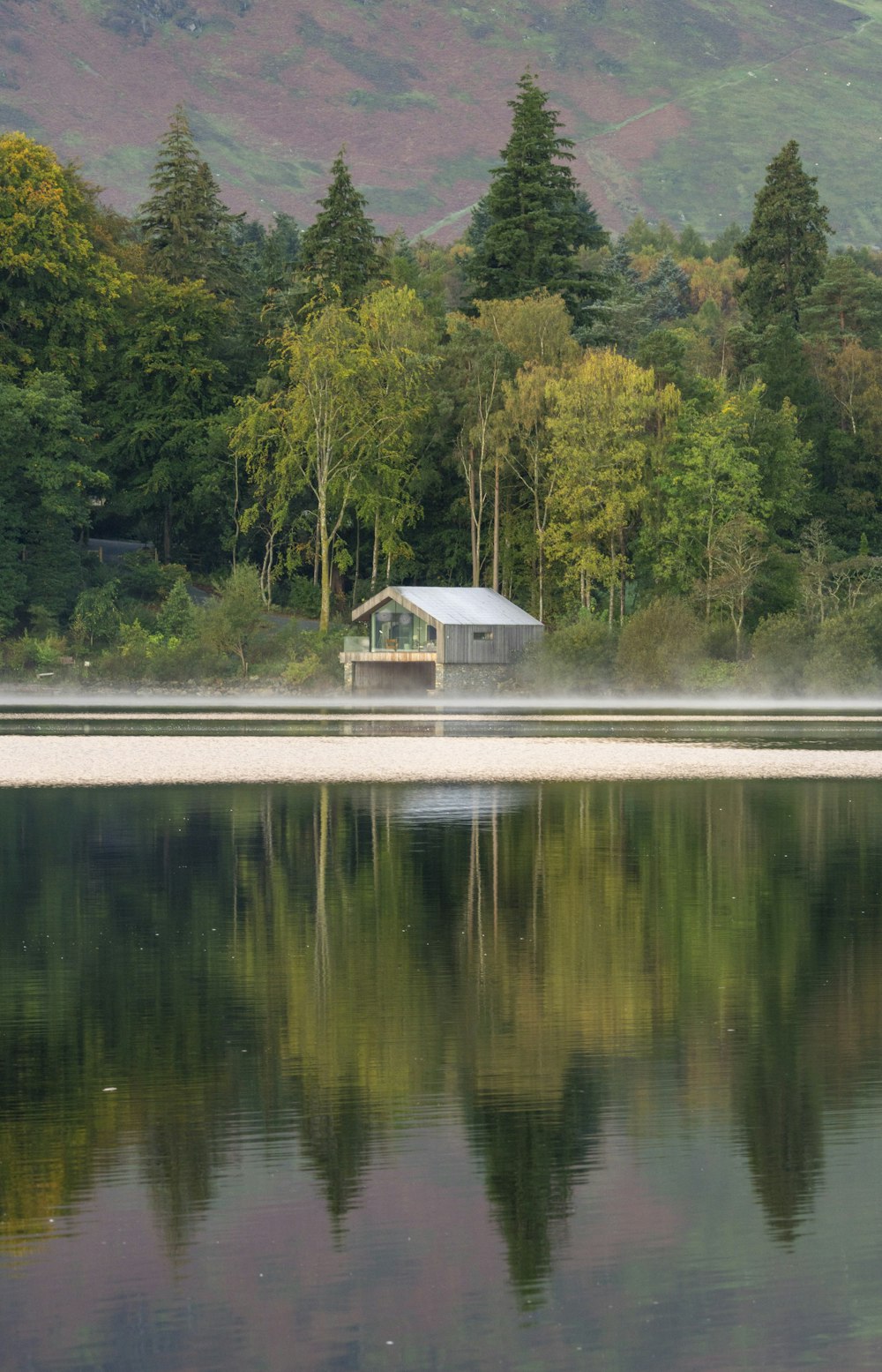 a small house on a lake surrounded by trees