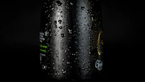 Close-up of a sleek Saryu Aqua bottle with water droplets on a dark green background