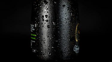 Close-up of Saryu Aqua bottle with water droplets on a dark green background.