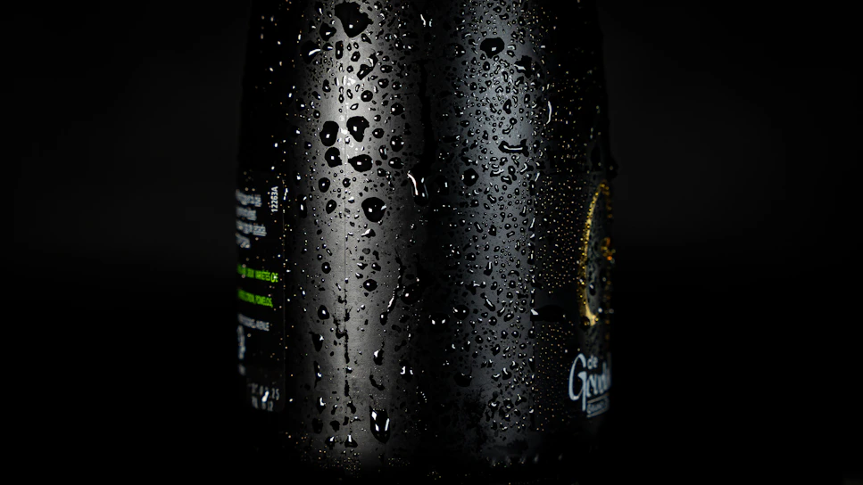 A vibrant close-up of a chilled Primewave beverage bottle with water droplets glistening under bright aqua lighting.