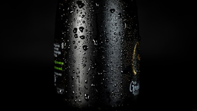 Close-up of a refreshing water droplet sliding down a transparent glass bottle branded with Hydrapure.