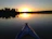 A serene kayak gliding through calm estuary waters at sunset with soft golden light.