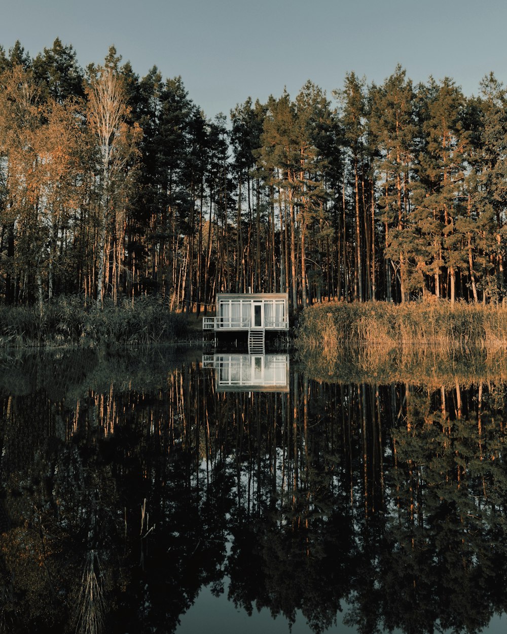 a small house sitting on top of a lake surrounded by trees