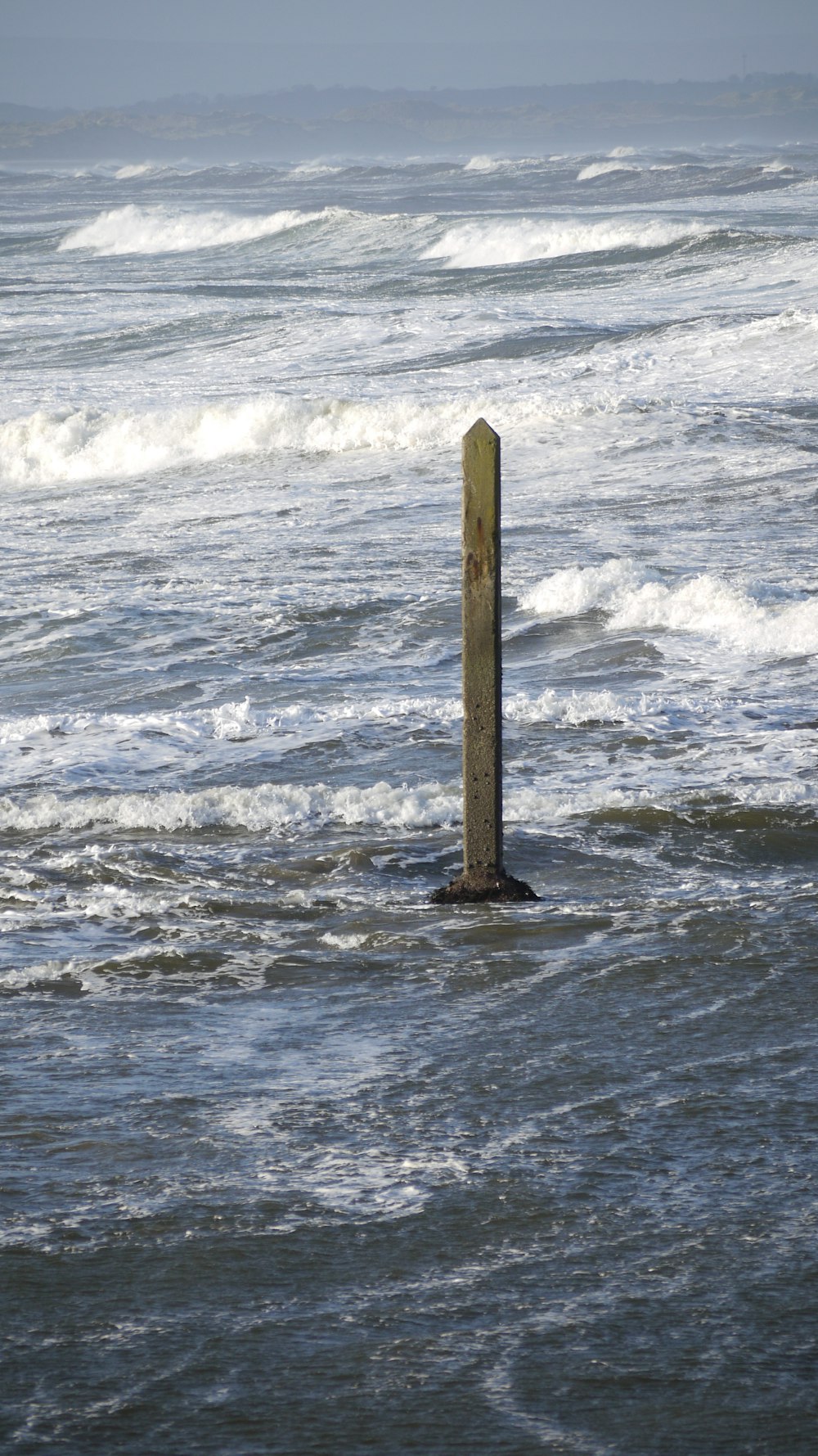 a wooden pole sticking out of the ocean