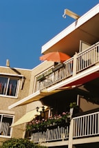 A friendly installer measuring a balcony for a custom awning under a bright sky.