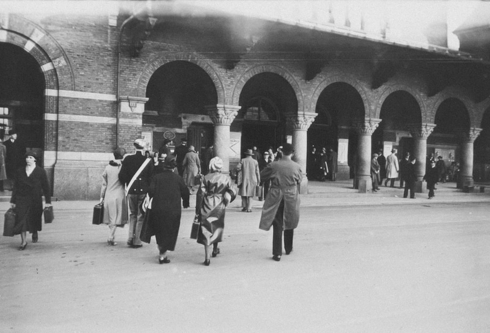 a black and white photo of people walking in a train station