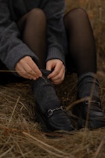 a person sitting on the ground tying a pair of shoes